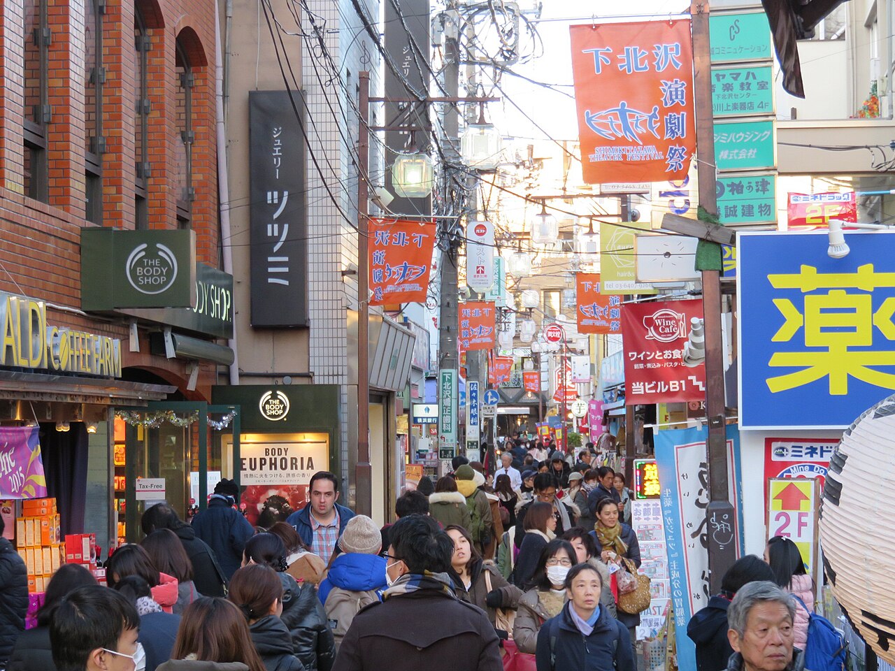 People and shop signs along a busy shopping street in Shimokitazawa, Tokyo.